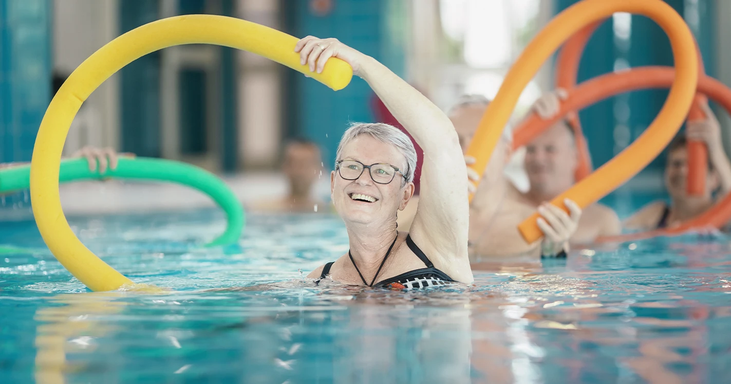Eine Rehabilitandin macht eine Übung mit einer Schwimmnudel im Bewegungsbad.
