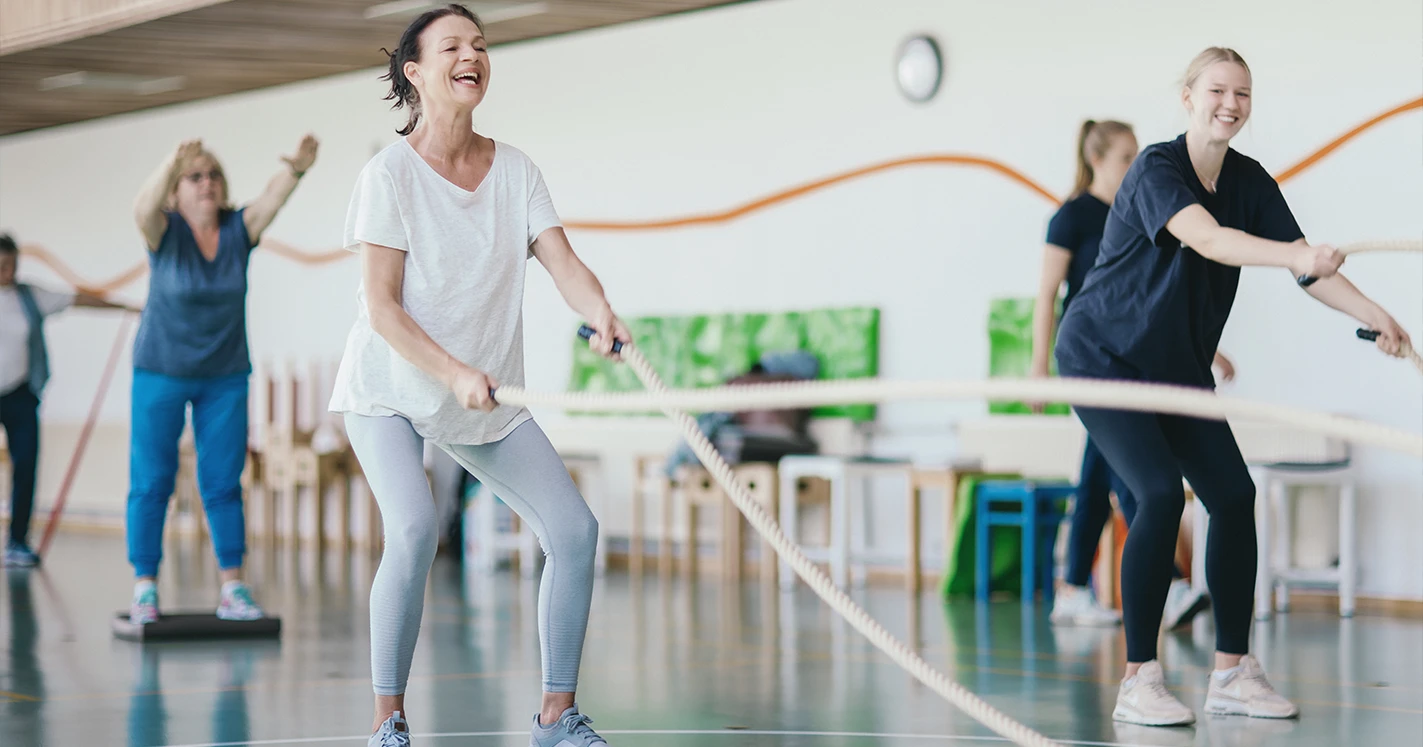 Rehabilitierende bei der Sporttherapie halten Seile in ihren Händen, um diese kraftvoll zu schwingen.