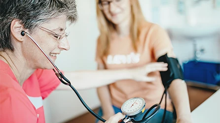 Eine Mitarbeiterin der Diagnostik misst den Blutdruck einer Rehabilitandin.